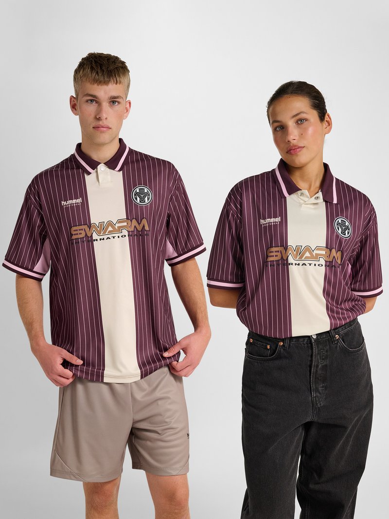 Junger Mann und Frau tragen passende bordeaux- und cremefarbene gestreifte Poloshirts mit dem "SWARM International"-Logo und stehen vor einem schlichten Hintergrund.