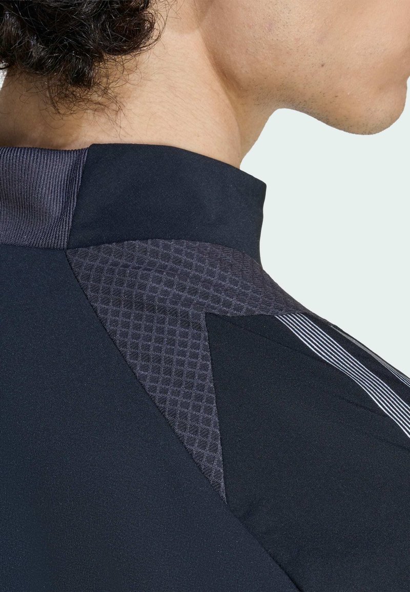 Black athletic shirt featuring a textured dark grey accent, ribbed collar, and white stripes for contrast. Close-up view of shoulder area.