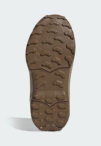 Καφέ ελαστική σόλα παπουτσιού με βαθιά σχέδια, που διαθέτει γεωμετρικό μοτίβο και υφασμένες περιοχές για πρόσφυση. Ανθεκτικό υλικό, στιβαρός σχεδιασμός.