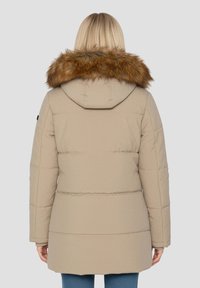 Beżowa kurtka puchowa z odpinanym kapturem z brązowego sztucznego futra. Posiada pikowany wzór i długość do połowy, wykonana z gładkiej tkaniny.