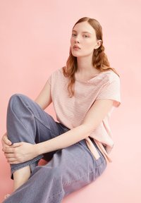 T-shirt rayé rose et blanc à manches courtes, associé à un pantalon en denim bleu clair ample. Tissu doux, coupe décontractée.