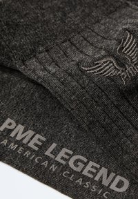Szara teksturowana tkanina z prążkowanym wzorem i haftowanym detalem skrzydła. Zawiera napis "PME LEGEND AMERICAN CLASSIC" w kontrastowym kolorze.