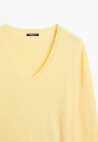 Gelber Cashmere-V-Ausschnitt-Pullover mit geripptem Kragen und Bündchen, weichem Griff und leichtem Design. Markenlabel innen sichtbar.