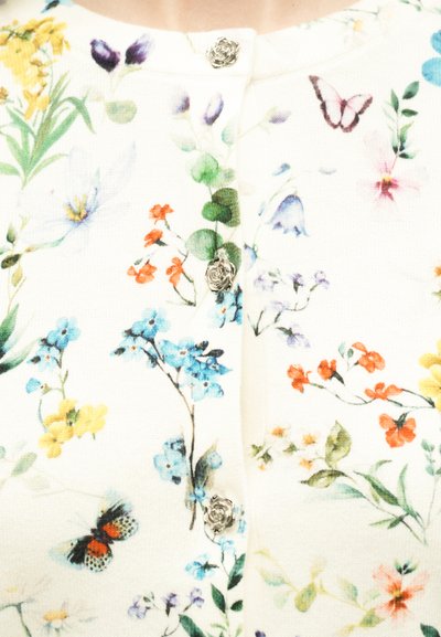 Λευκό ύφασμα με πολύχρωμα λουλουδενια και πεταλούδες μοτίβα, με μικρά ασημί κουμπιά σε σχήμα τριαντάφυλλου κατά μήκος του κέντρου.