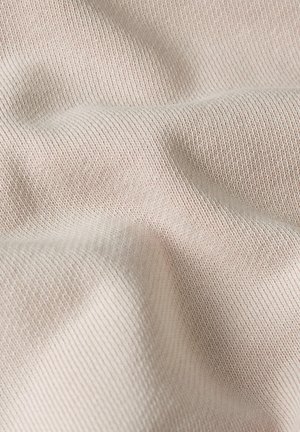 Soft beige knitted fabric with fine texture and gentle folds creating subtle shadows and depth.