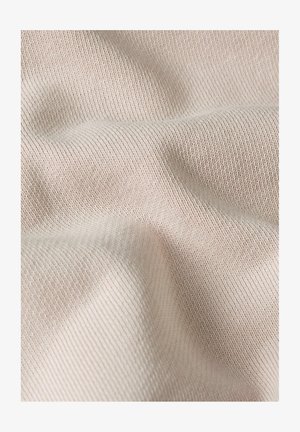 Soft beige knitted fabric with fine texture and gentle folds creating subtle shadows and depth.