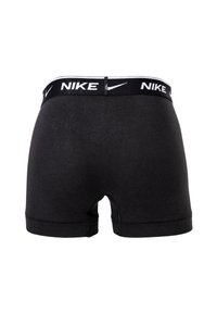 Schwarze Baumwoll-Boxershorts mit einem elastischen Bund, auf dem "NIKE" in Weiß steht. Glatte Textur, Oberschenkel-lange Geschnitten, einfaches Design.