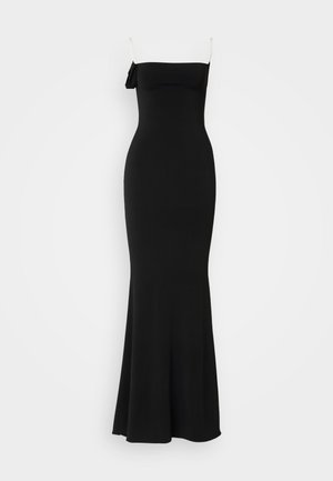 Black, form-fitting, floor-length dress with spaghetti straps and a bow detail on one shoulder. Made from smooth, stretchy fabric.