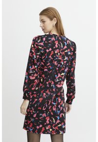 Schwarzes Kleid mit einem bunten abstrakten Muster in Rot, Pink, Blau und Gelb, mit langen Ärmeln und einer taillierten Silhouette.
