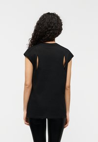 Μαύρο κοντομάνικο t-shirt με λεπτομέρειες κοψίματος στους ώμους, κατασκευασμένο από απαλό ύφασμα, με άνετη εφαρμογή και στρογγυλεμένο τελείωμα.