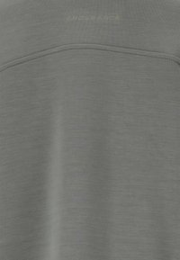 Grå idrottströja i mjukt, texturerat tyg med en horisontell söm och ordet "ENDURANCE" präglat i ljusgrönt på den övre delen.