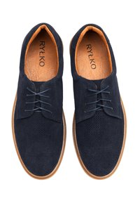Zapatos de ante azul marino con parte superior perforada, suela de goma marrón contrastante y cordones azul marino. Nombre de la marca inscrito en la plantilla naranja.