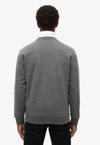 Sudadera gris con cuello redondo y puños acanalados. Tejido suave con una textura lisa. Mostrada por la parte de atrás, con un diseño liso.