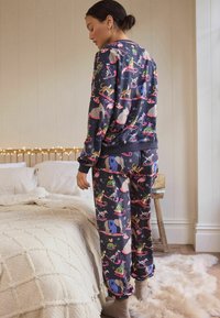 Mörkblå pyjamasset med ett lekfullt djurmönster. Tillverkat av mjukt tyg med en avslappnad passform, elastiska ärmslut och midjeband.