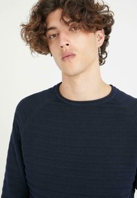 Suéter de punto texturizado azul marino con rayas horizontales, cuello redondo y mangas raglán, confeccionado con una suave tela tejida.