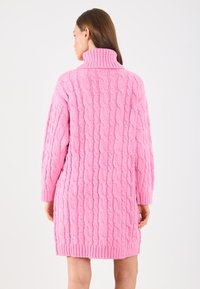 Ružičasta pletena haljina sa lažnim turtleneck ovratnikom, koja ima teksturirani uzorak i rebraste rukave i rub, dužine do sredine butina.