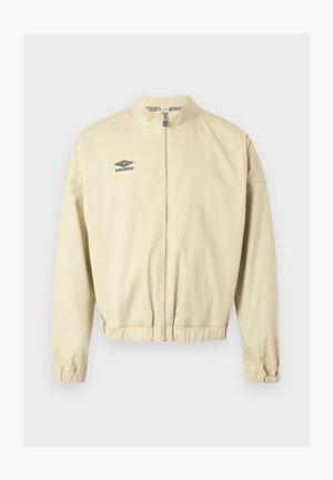 Beige Reißverschlussjacke mit Stehkragen, elastischen Bündchen und Saum, mit einem kleinen schwarzen Umbro-Logo auf der linken Brust.
