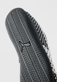 Μαύρη λαστιχένια σόλα παπουτσιού με υφή στο πέλμα και λογότυπο Puma, συνδυασμένη με λευκό και μαύρο πουά επάνω μέρος.