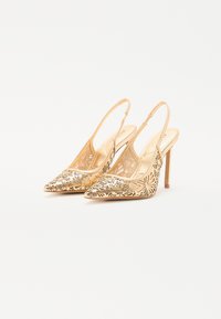 Gylne slingback hæler med spiss tå og utskåret blomstermønster. Slitesterk, glatt overflate; slank hæl; minimalistisk design.