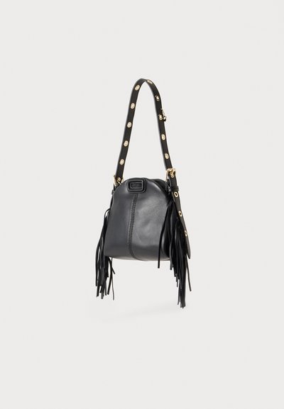 Sac à main en cuir noir avec des œillets dorés sur la sangle et de longues franges de chaque côté, présenté sur un fond uni.