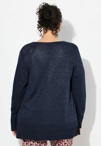 Navyblauer oversized Strickpullover mit strukturiertem Finish, breitem Rundhalsausschnitt, langen Ärmeln und gerippten Saumdetails.
