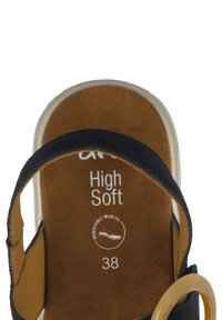 Sandal nero con una morbida soletta color tan, dotato di una fascia larga e un accento circolare color tan. Taglia 38 indicata sulla soletta.