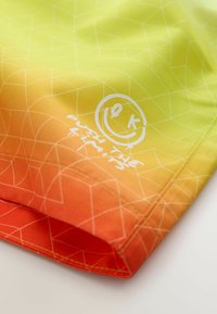 Costumi da bagno con una sfumatura che va dal giallo all'arancione, caratterizzati da un motivo a linee geometriche e grafiche bianche, tra cui una faccina sorridente e del testo.