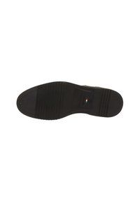 Semelle en caoutchouc noir d'une chaussure habillée pour homme avec des motifs de semelle et un petit drapeau italien près du centre.