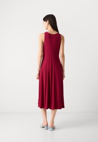 Vihreä hihaton midi-mekko, jossa on istuva yläosa ja levenevä helma. Ominaisuuksiin kuuluvat pystysuora ribbitekstuuri ja huomaamaton vetoketju takana.