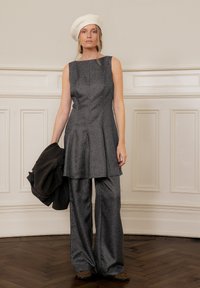 Gray, textured fabric outfit featuring a sleeveless top with pleats and wide-leg pants, complemented by a white beret and dark jacket.