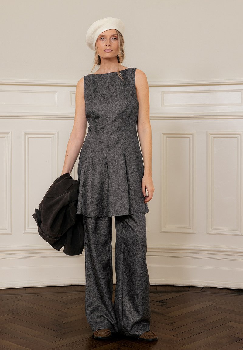 Gray, textured fabric outfit featuring a sleeveless top with pleats and wide-leg pants, complemented by a white beret and dark jacket.