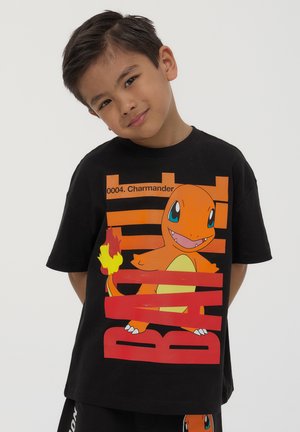 T-shirt in cotone nero con una grafica di Charmander in arancione e giallo, con lettering rosso in grassetto che dice "0004. Charmander" e "BATTLE."