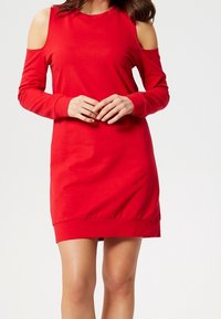Vestido rojo de manga larga con cortes en los hombros, ajuste relajado y dobladillo elástico. Hecho de una tela suave y elástica para mayor comodidad.