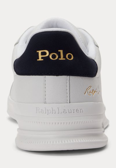 Λευκό αθλητικό παπούτσι Ralph Lauren από πίσω με ναυτικό μπλε ταμπελάκι στη φτέρνα που διαθέτει χρυσή γραμματοσειρά "Polo" και ανάγλυφο "Ralph Lauren" στη σόλα.