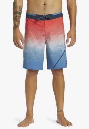 Maillots de bain dégradés rouge et bleu avec un motif éclaboussé, dotés d'une taille à cordon de serrage et d'accents latéraux, fabriqués en tissu léger.