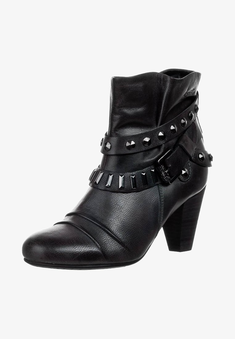 Bottine en cuir noir à talon empilé, avec des brides décoratives ornées de clous ronds et rectangulaires en métal, et un accent boucle.