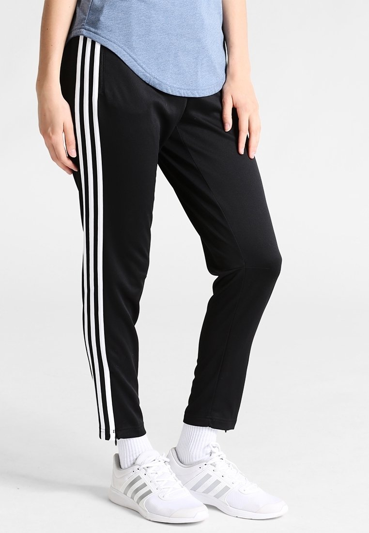Pantalons de sport noirs avec trois bandes verticales blanches sur les côtés, fabriqués à partir d'un tissu lisse et léger. Ajustement à la cheville.