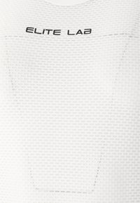 Hvid sports-top med tekstureret stof, der har mærkenavnet "ELITE LAB" i sort på tværs af brystet. Enkel, tætsiddende design.