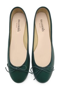 Grüne Ballerinas mit glatter Oberfläche, runder Zehenform und kleinen Schleifendetails auf der Vorderseite. Das Innere ist mit beiger Innenauskleidung versehen.