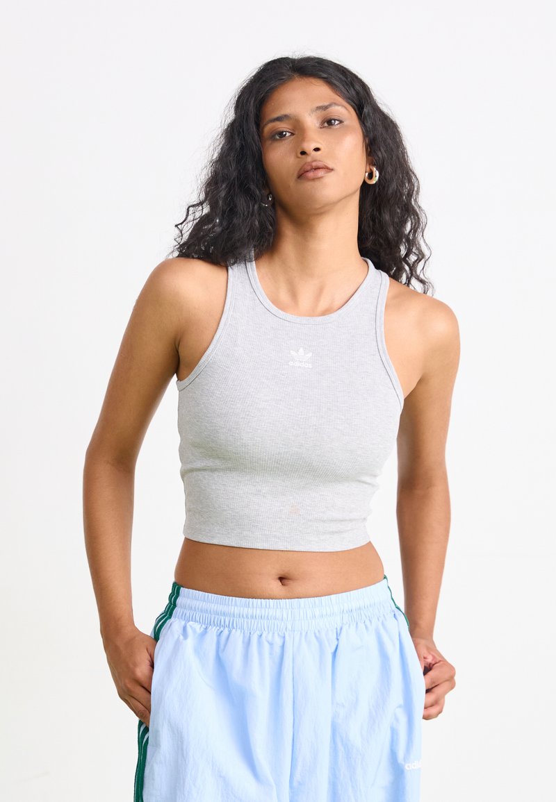 Hall kõrgusega hall ribaga crop tank top ümmarguse kaelaajaga ja väikese valge logoga keskel. Sobib kergete siniste elastse vöökohtadega pükstega.