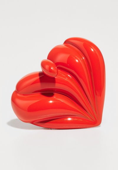 Red heart-shaped object with a glossy finish, featuring wavy, curved forms and a prominent rounded accent on the top.