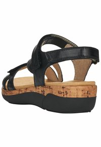 Sandalia de cuero negra con plantilla de corcho, suela texturizada, correas ajustables y suela de goma negra, diseñada para brindar comodidad y estabilidad.