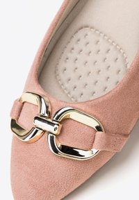 Chaussure plate en suède rose blush avec un bout pointu, ornée d'une boucle métallique dorée et d'un intérieur texturé dans une teinte neutre.