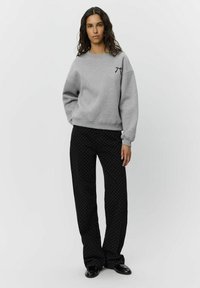 Gray sweatshirt with a crew neckline and elastic cuffs, paired with black polka dot pants. Fabric texture appears soft and casual.