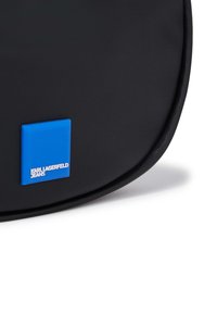 Black leather crossbody bag with a smooth texture, featuring a blue rectangular logo accent and white "KARL LAGERFELD JEANS" text.