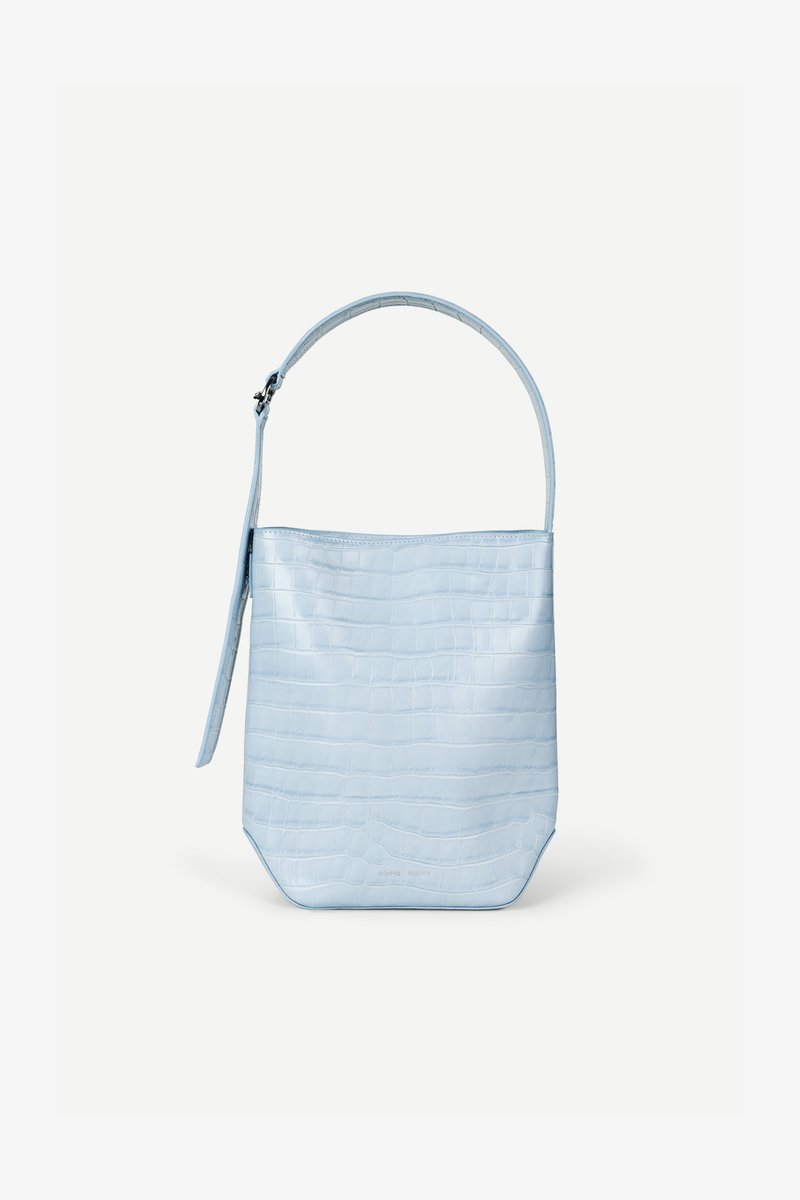 Τσάντα ώμου γαλάζιου χρώματος με υφή κροκόδειλου, ορθογώνιο σχήμα, μία λαβή στο πάνω μέρος και λουρί που κρέμεται στο πλάι, σε απλό λευκό φόντο.
