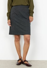 Grå tweed blyertskjol med en figursydd design, knä-lång, med en slät textur och ett elastiskt midjeband. Bärs med mörka glänsande skor.