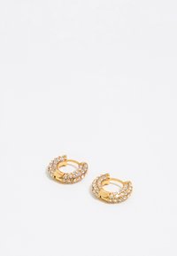 Boucles d'oreilles en or en forme de créole ornées de cristaux transparents, présentant un design courbé et une fermeture à charnière sécurisée, affichant une texture lisse et brillante.