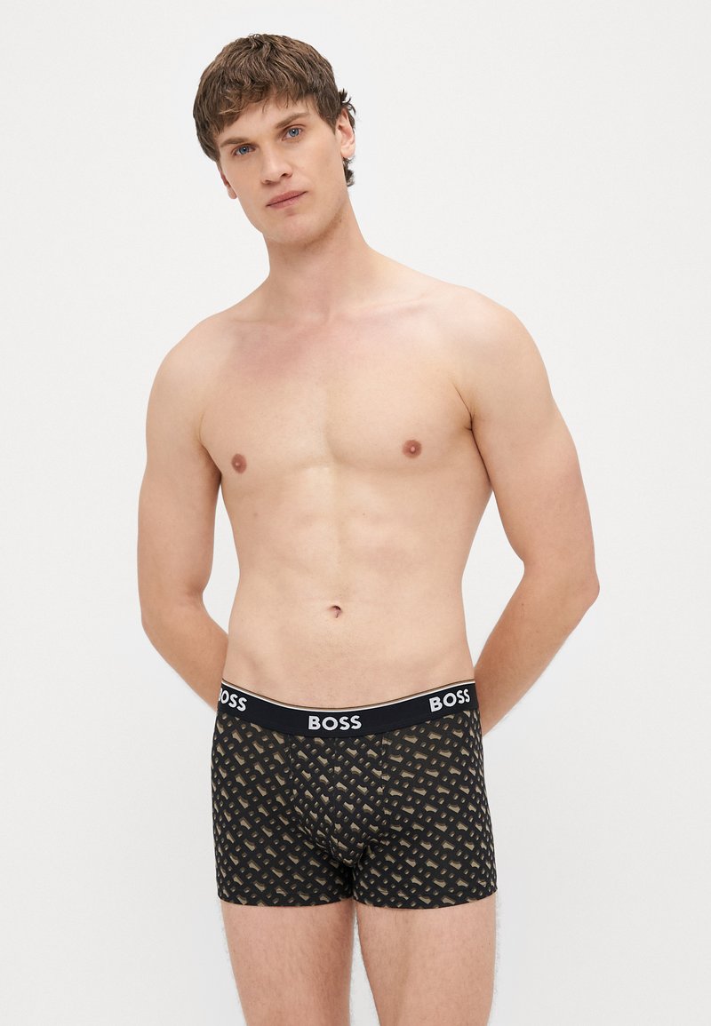 Μαύρα ανδρικά εσώρουχα τύπου μποξέρ με γεωμετρικό μοτίβο, κατασκευασμένα από μαλακό ύφασμα, με λωρίδα λογότυπου στη μέση και εφαρμοστή σχεδίαση.