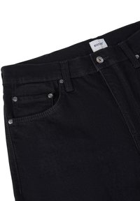 Jeans de denim negro con un diseño clásico de cinco bolsillos, cremallera y herrajes plateados en contraste. La tela tiene una textura suave.